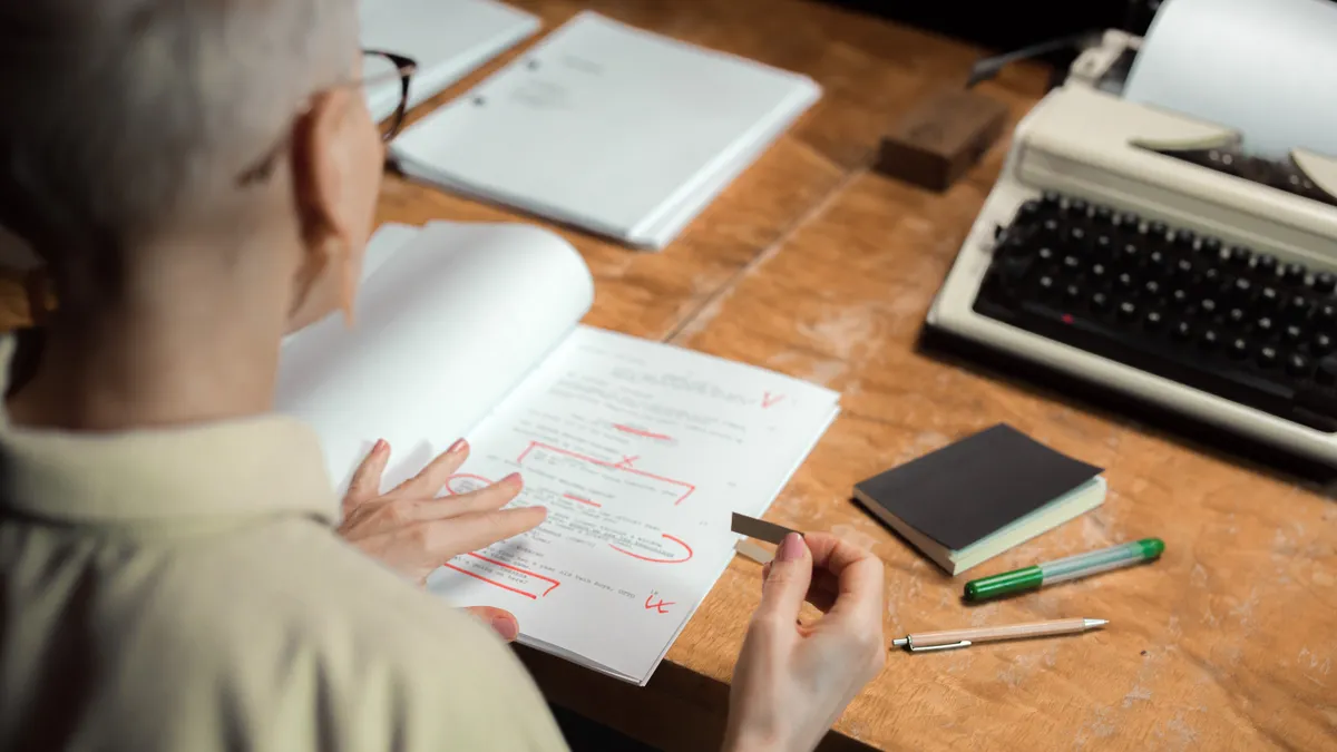 Person marking up a printed draft at a desk