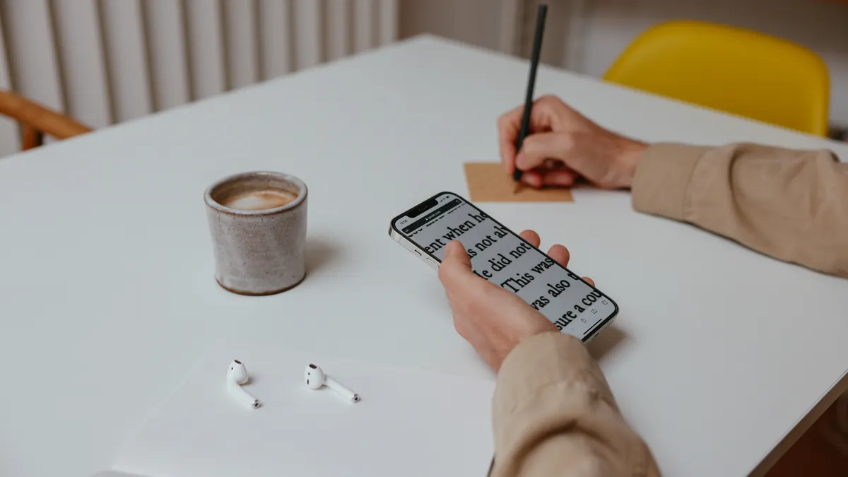 Writesonic Review — A Person Writing While Holding His Smartphone